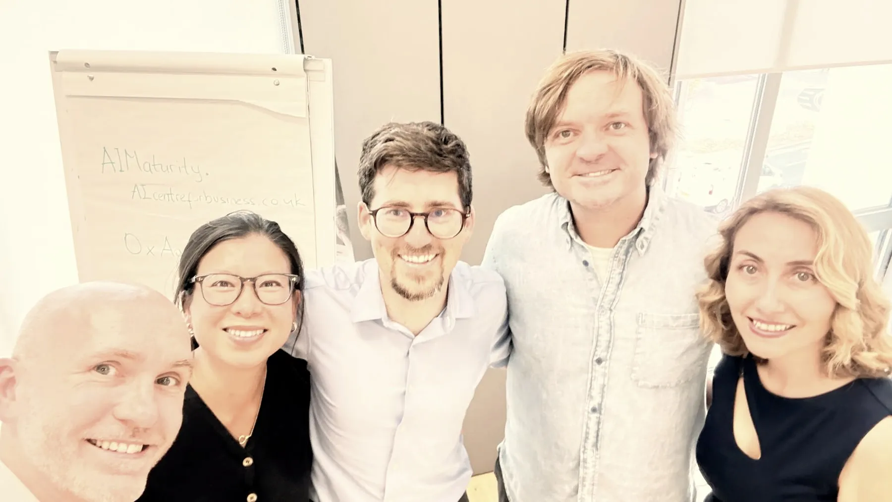 Five people standing together in front of a flipchart at the close of the first Oxford Agentic Bootcamp.
