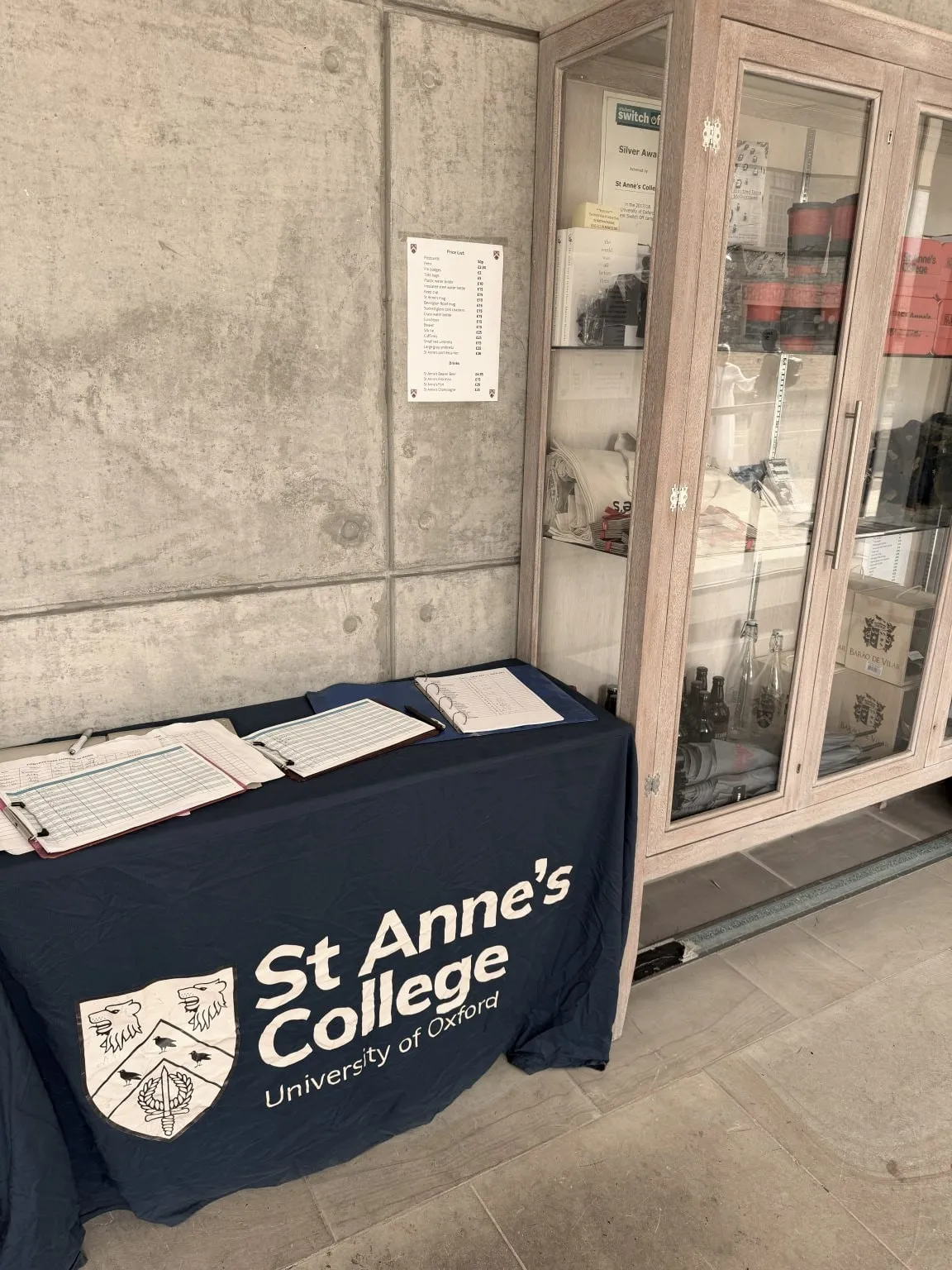 A registration desk draped in a St Anne's College, University of Oxford tablecloth, with sign-in sheets laid out ready for arrivals.